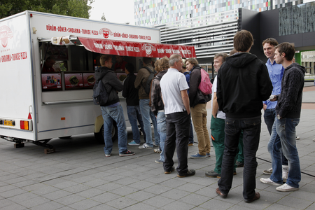 806572 Afbeelding van studenten bij een Turkse pizza- en shoarmakraam op de Heidelberglaan te Utrecht.